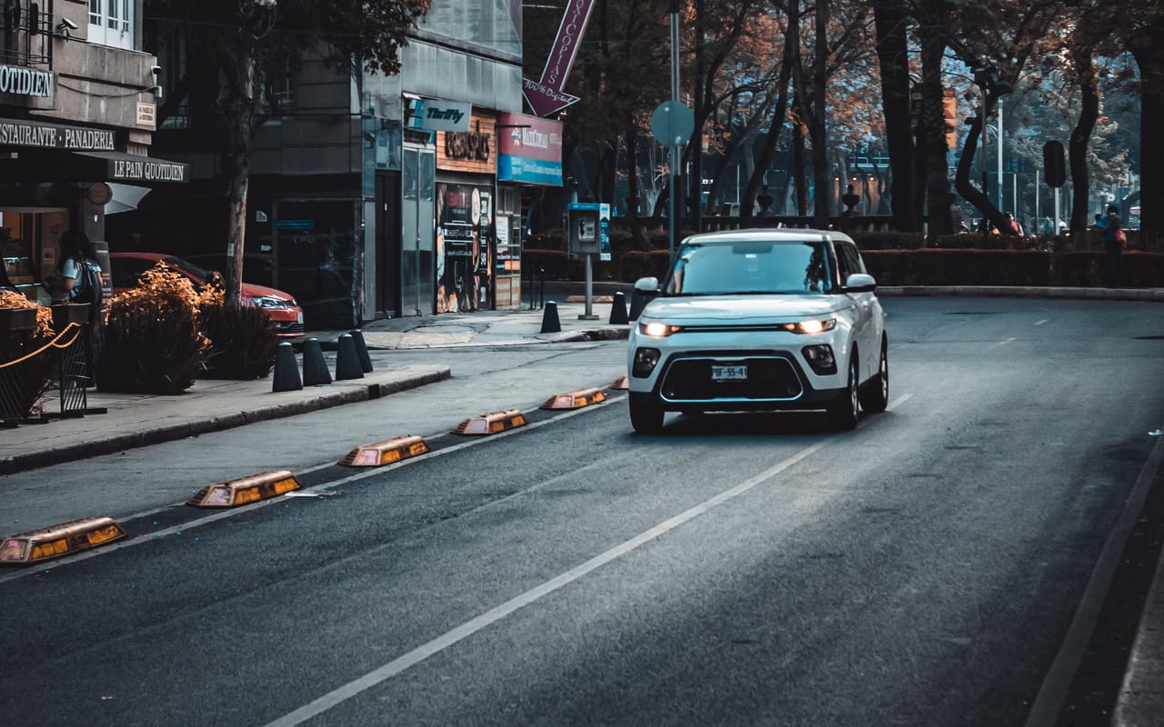 Carro trafegando em avenida arborizada de centro urbano